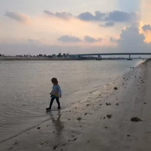 My daughter walking at the edge of the water near our rented apartment