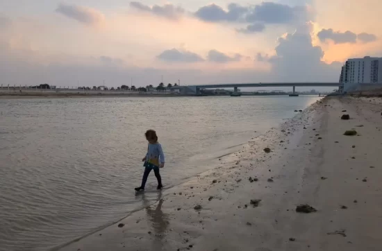 My daughter walking at the edge of the water near our rented apartment