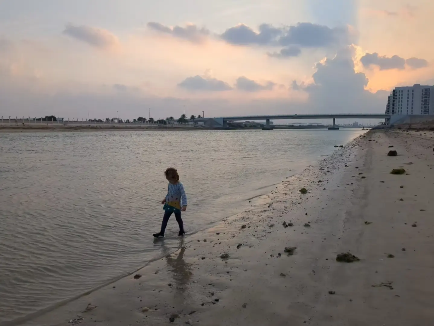 My daughter walking at the edge of the water near our rented apartment